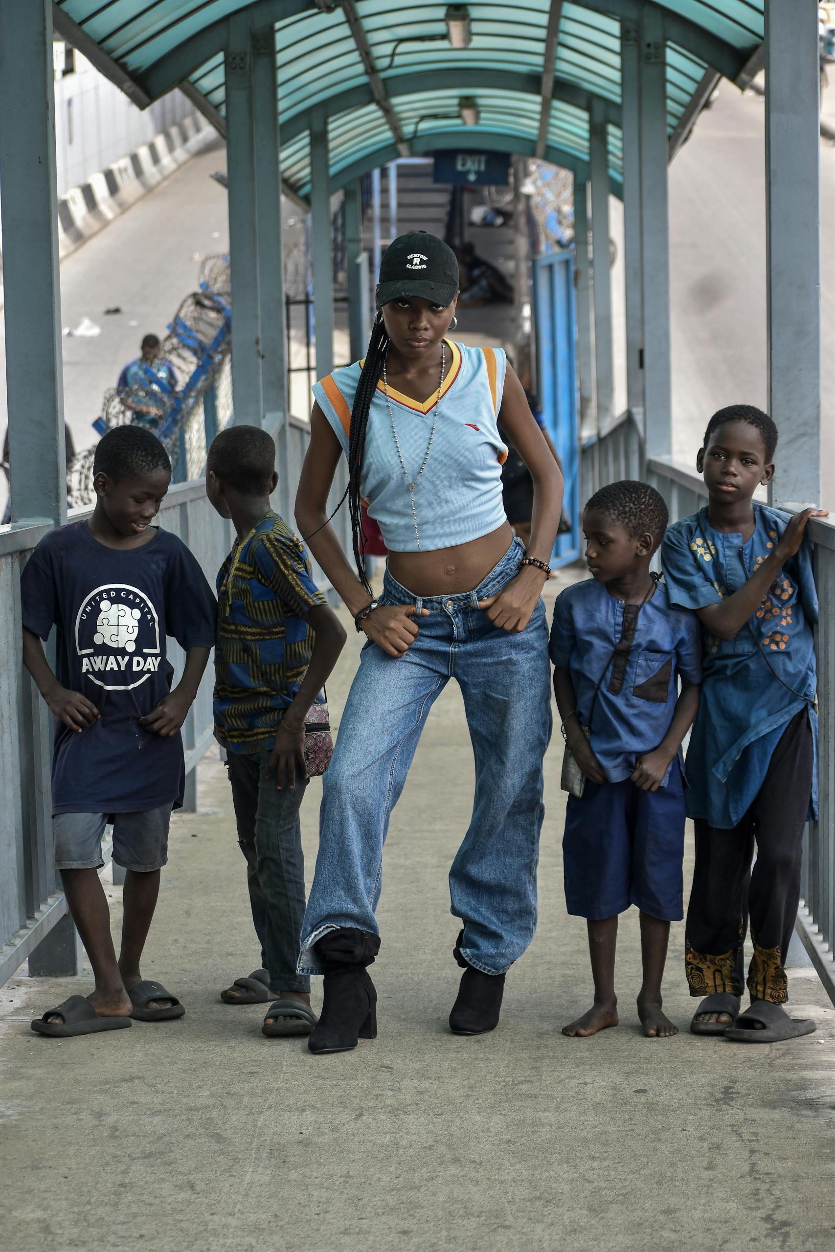Fashionable woman with children on urban bridge, casual style.
